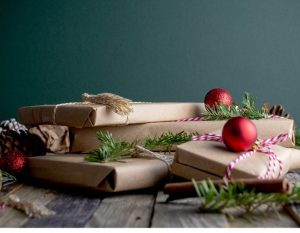 Multiple xmas gifts in brown paper wrap with red baubles on top and green decoration