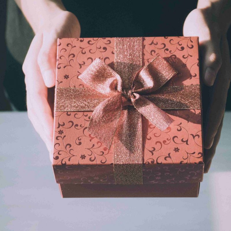 Woman's hands holding red present with bow